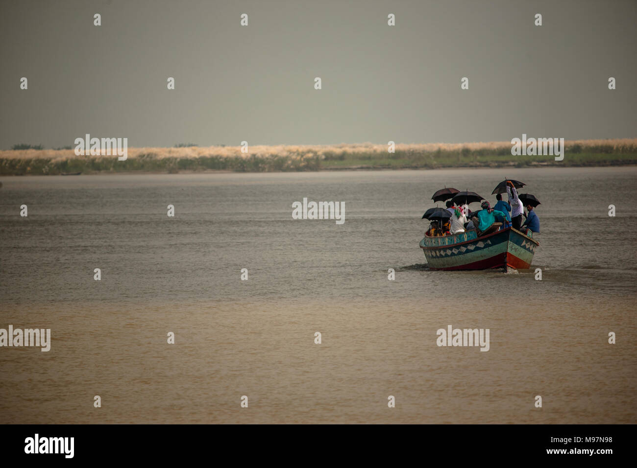 Un taxi de l'eau non conventionnelle transporte une cargaison de personnes qui utilisent des parapluies pour bien couvrir l'ensemble de la rivière Padma, le Bangladesh. Banque D'Images