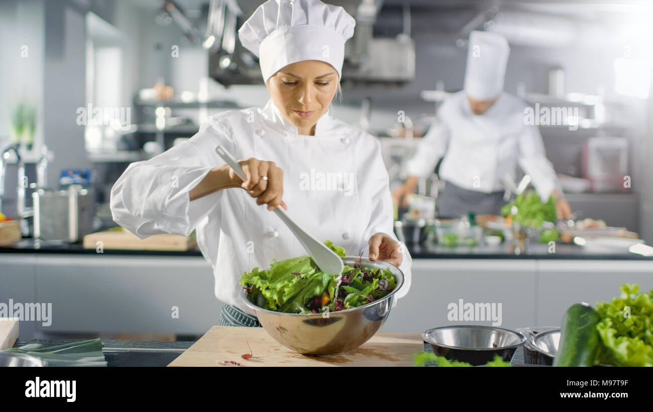 Dans un célèbre restaurant femme cuisinière prépare la salade. Elle travaille dans une grande cuisine moderne. Banque D'Images