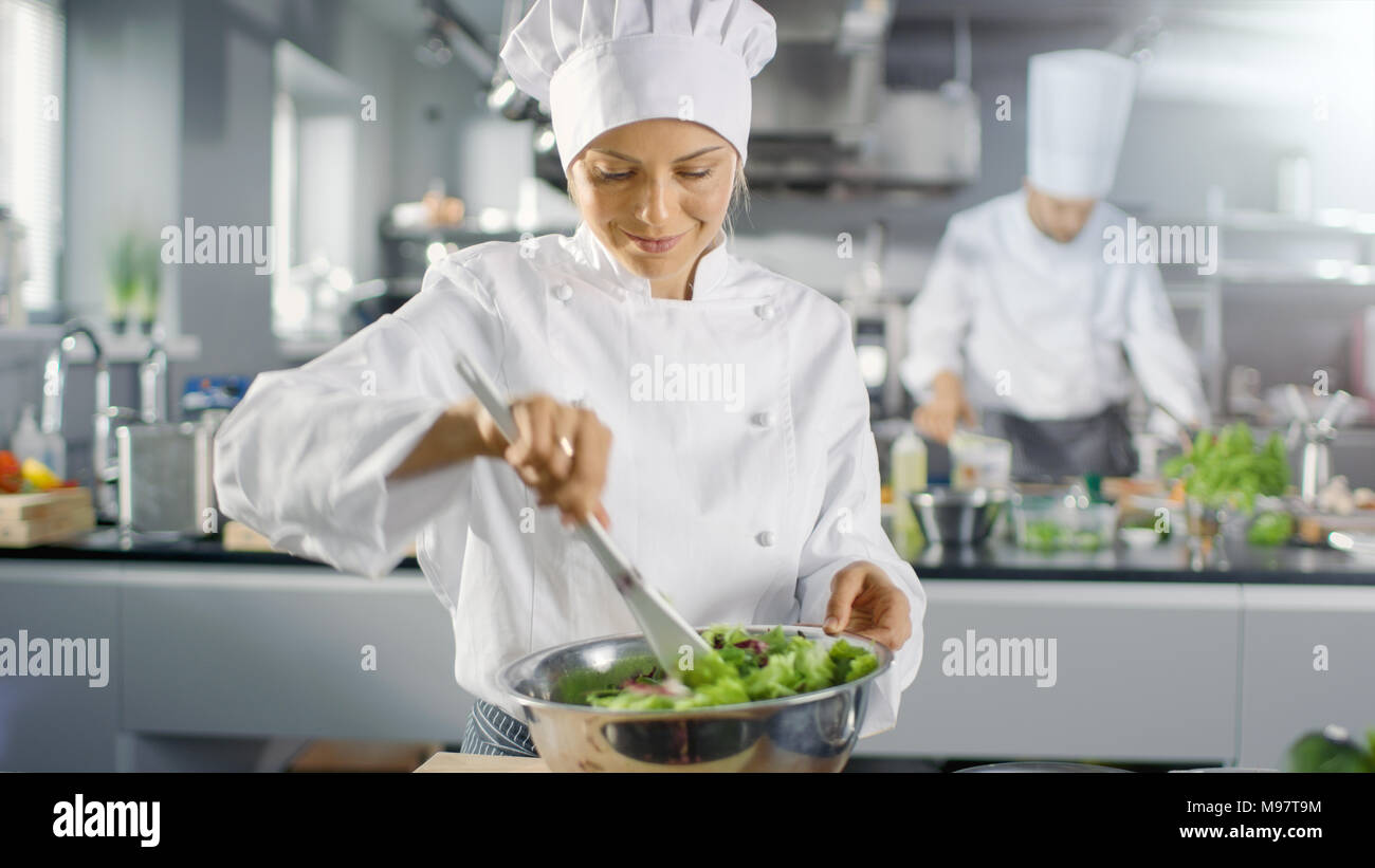 Dans un célèbre restaurant femme cuisinière prépare la salade. Elle travaille dans une grande cuisine moderne. Banque D'Images