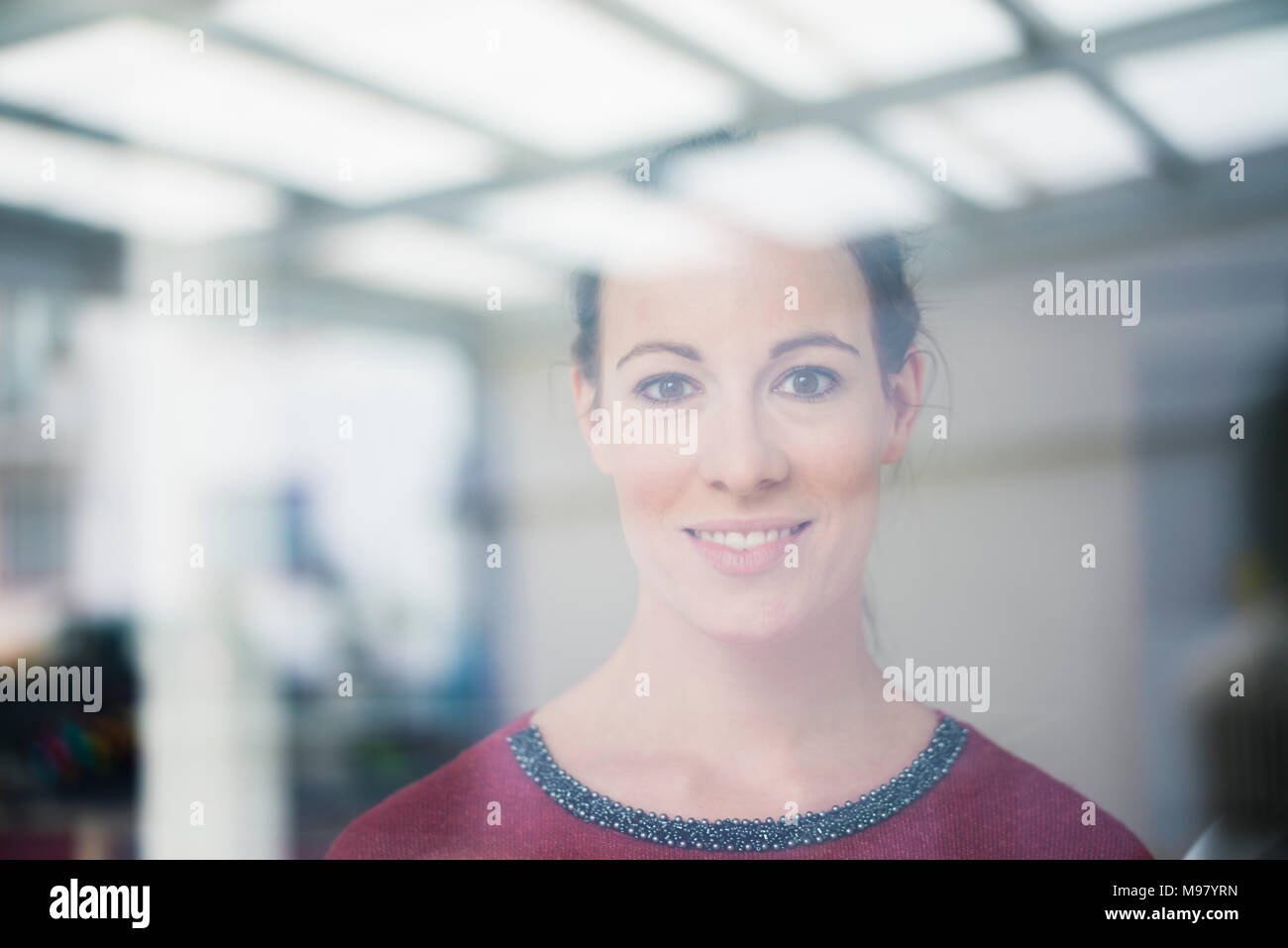 Portrait of smiling woman looking out of window Banque D'Images