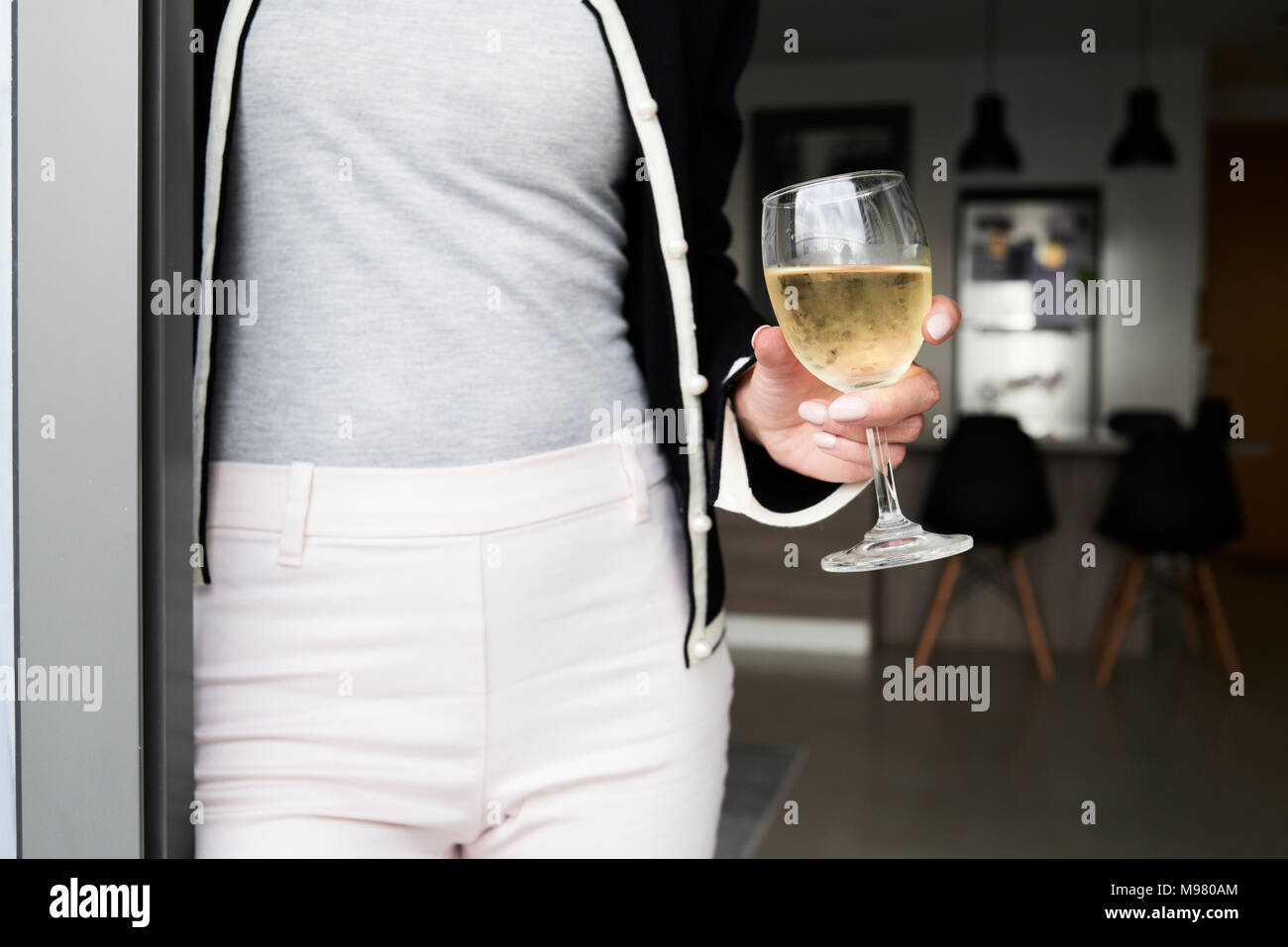 Détail de la femme tenant un verre de vin à la maison. Appartement moderne. Banque D'Images