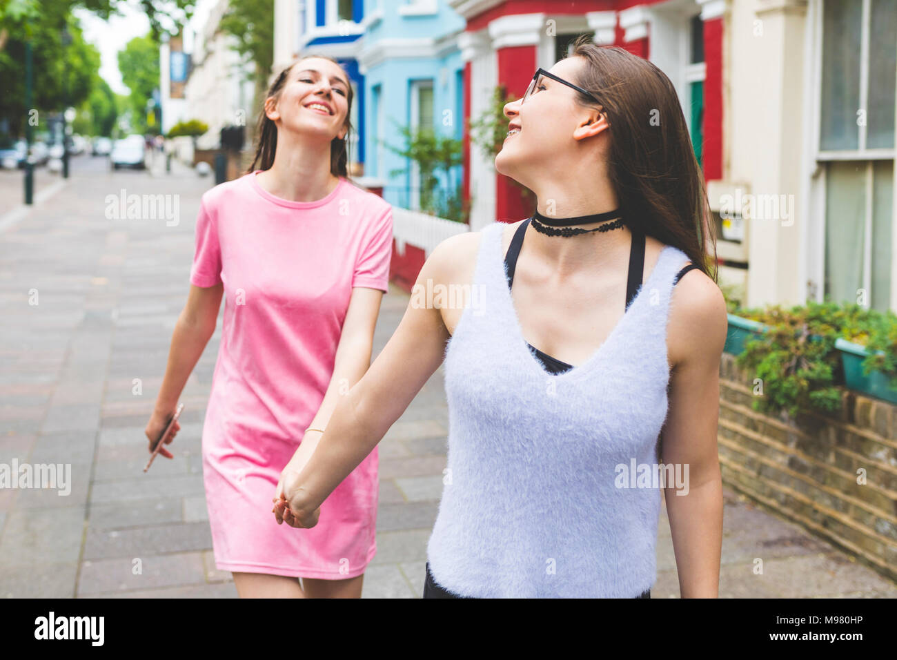Deux teenage girls marche main dans la main dans la ville Banque D'Images