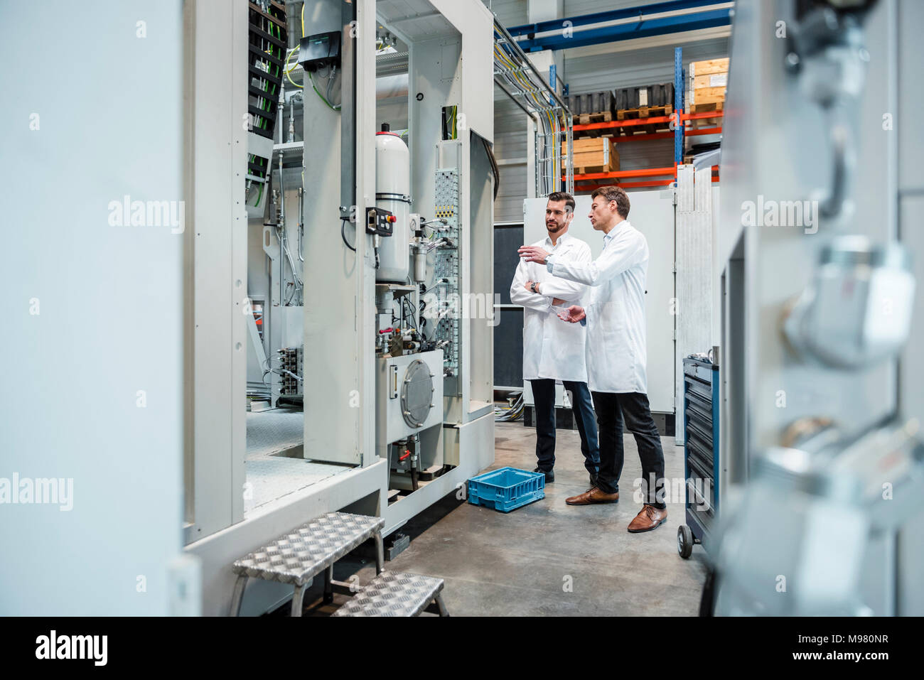 Deux hommes portant des blouses de laboratoire parler en usine Banque D'Images