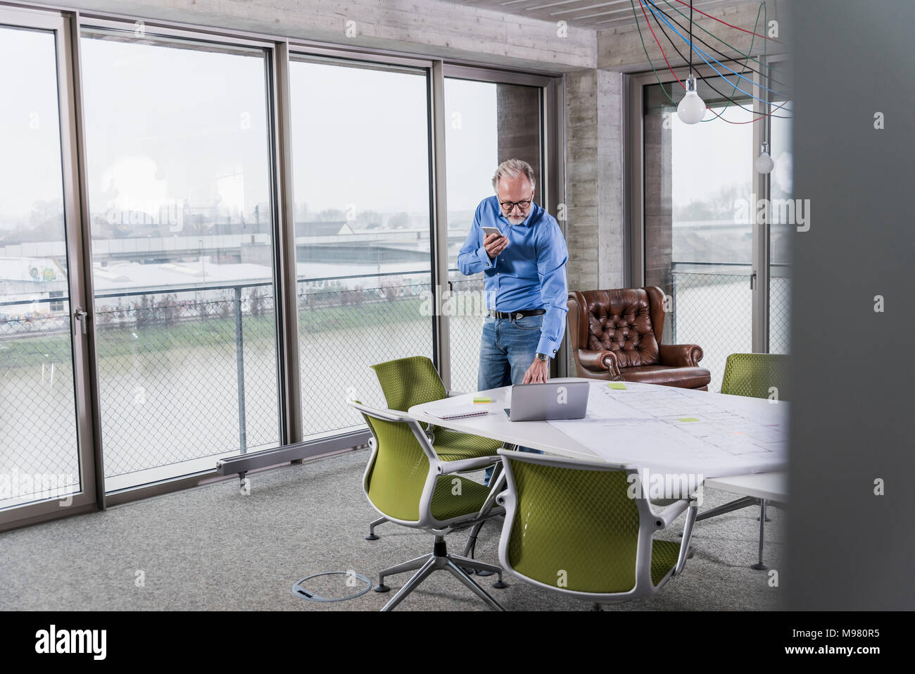Mature businessman using laptop and smartphone dans la salle de conférence in office Banque D'Images