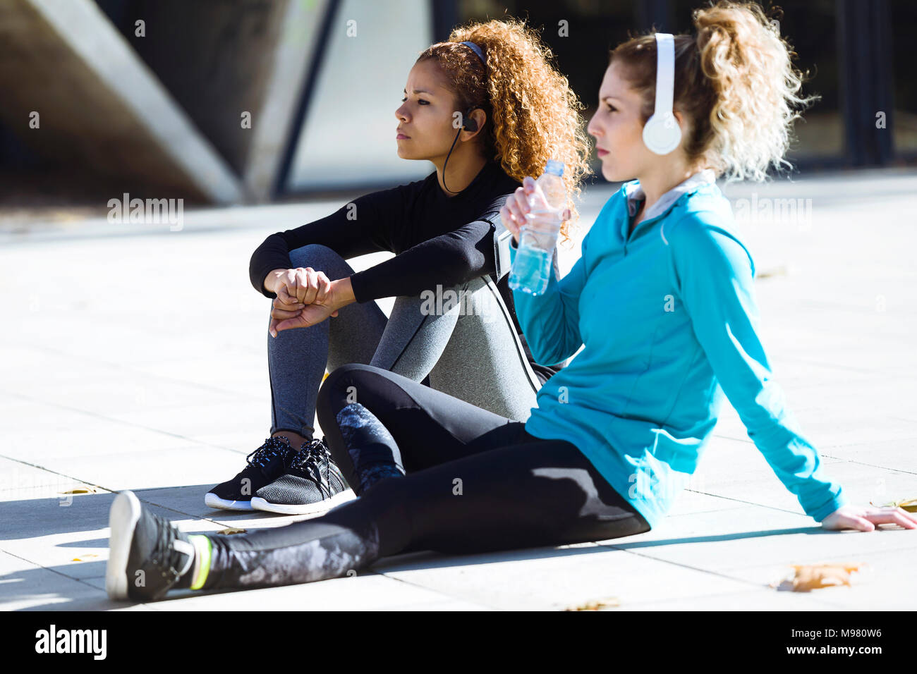 Deux jeunes femmes sportives ayant une pause à écouter de la musique Banque D'Images