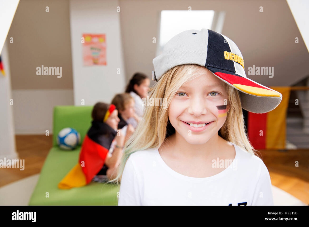 Portrait d'une fille avec de la peinture pour le visage et le chapeau allemand avec des amis en arrière-plan Banque D'Images