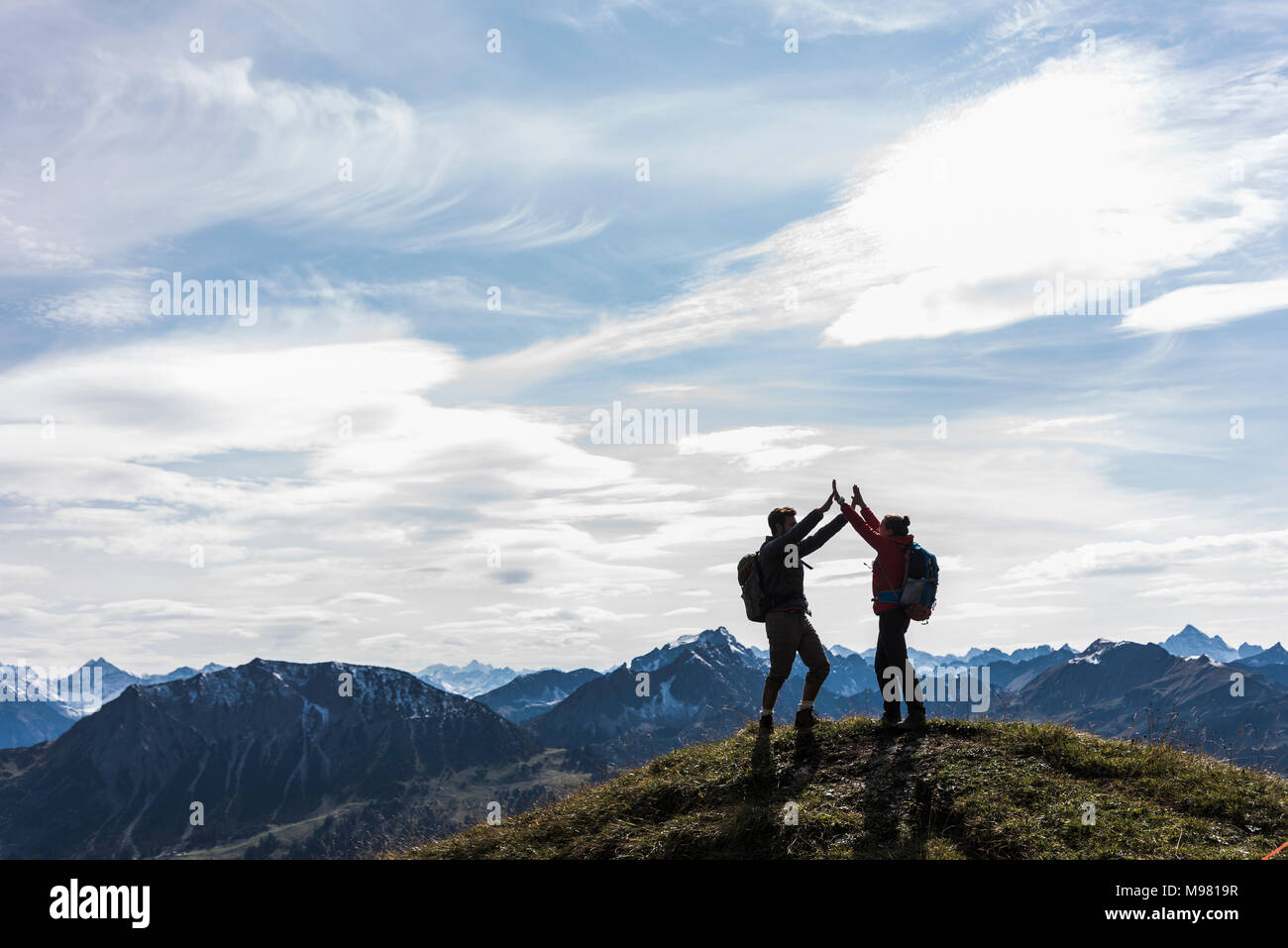 Autriche, Tyrol, jeune couple standing in mountainscape cheering Banque D'Images
