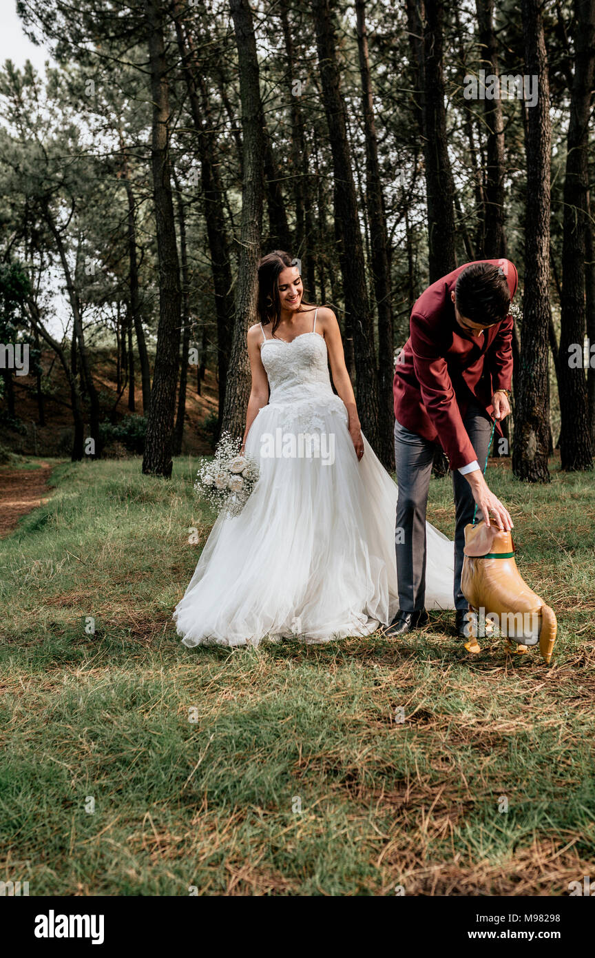 Mariée et le marié en forêt avec ballon en forme de chien rigolo Banque D'Images