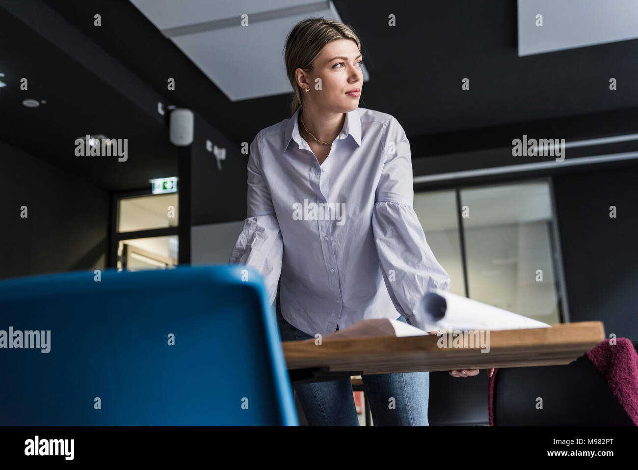 Young woman at table in office penser Banque D'Images