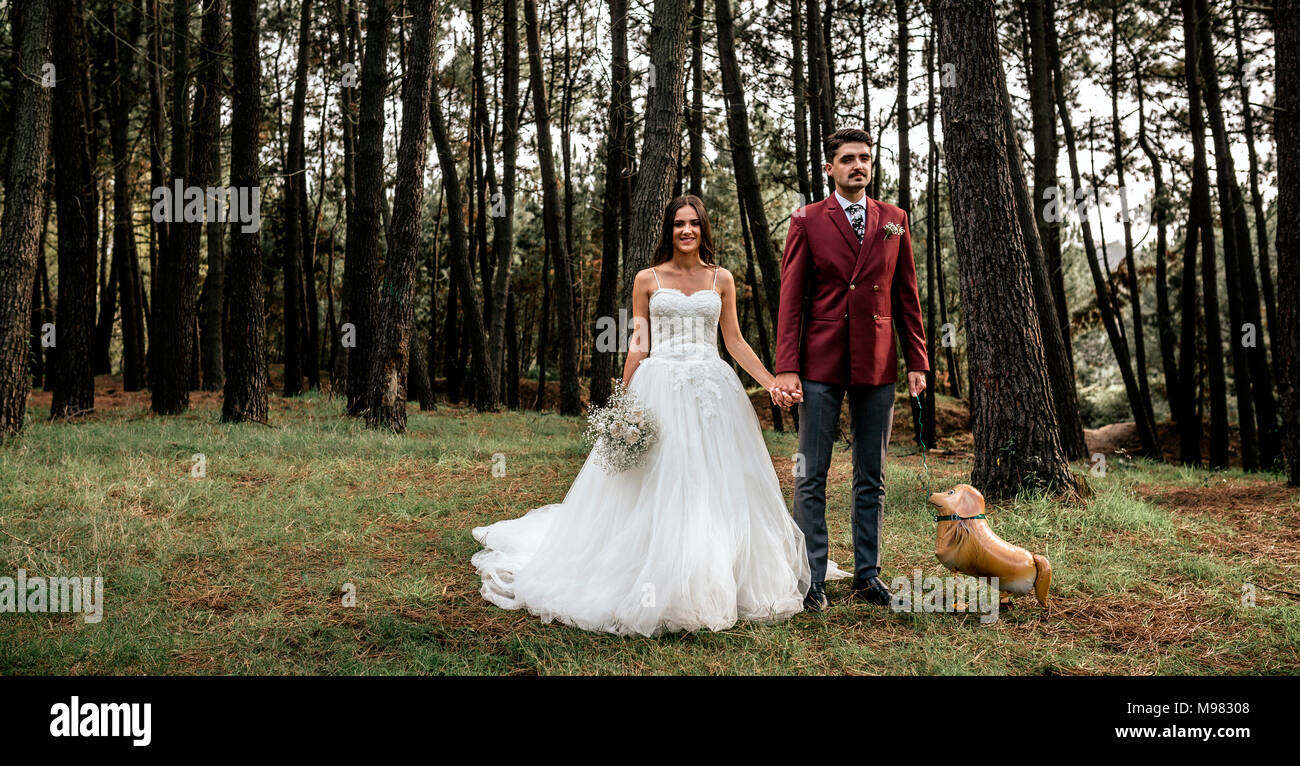 Heureux couple standing in forest avec drôle ballon en forme de chien Banque D'Images