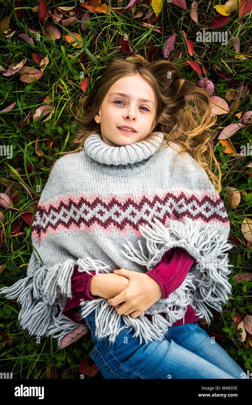 Portrait of Girl wearing poncho gisant sur prairie d'automne Banque D'Images
