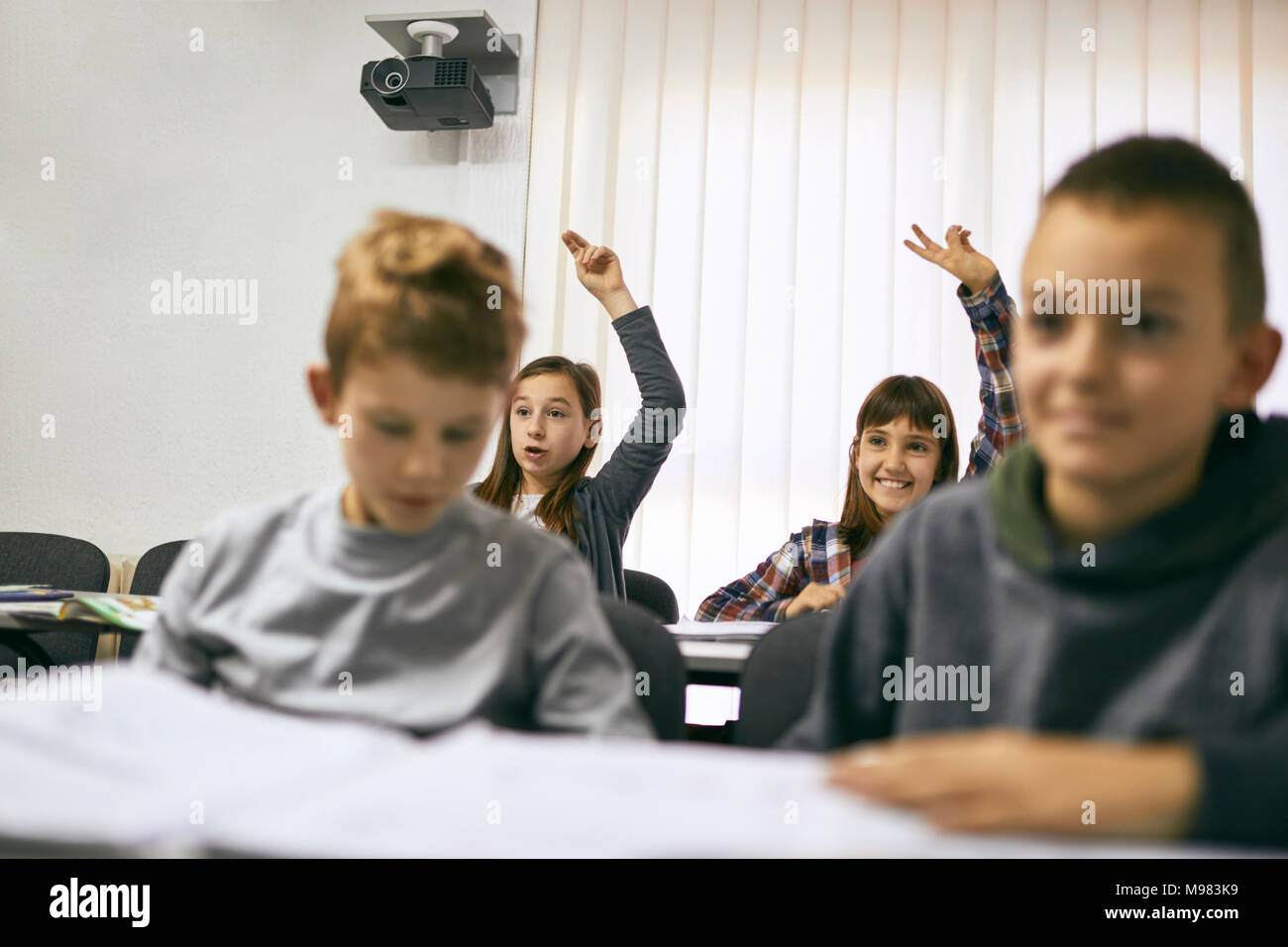 Étudiants en classe avec deux filles lèvent la main Banque D'Images