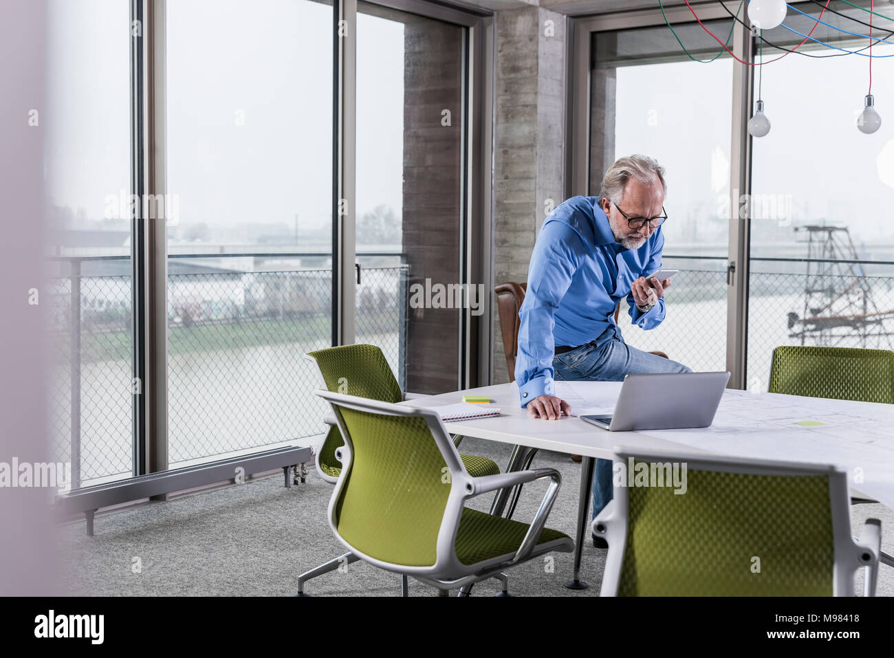 Mature businessman using laptop and smartphone dans la salle de conférence in office Banque D'Images