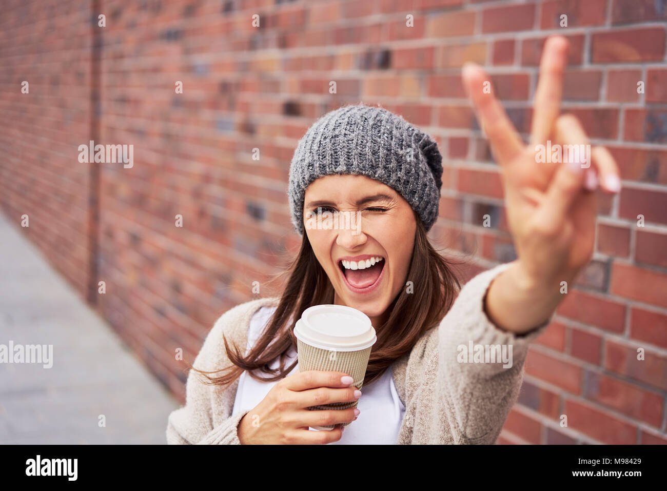 Portrait de jeune femme avec du café pour aller montrant la victoire Banque D'Images