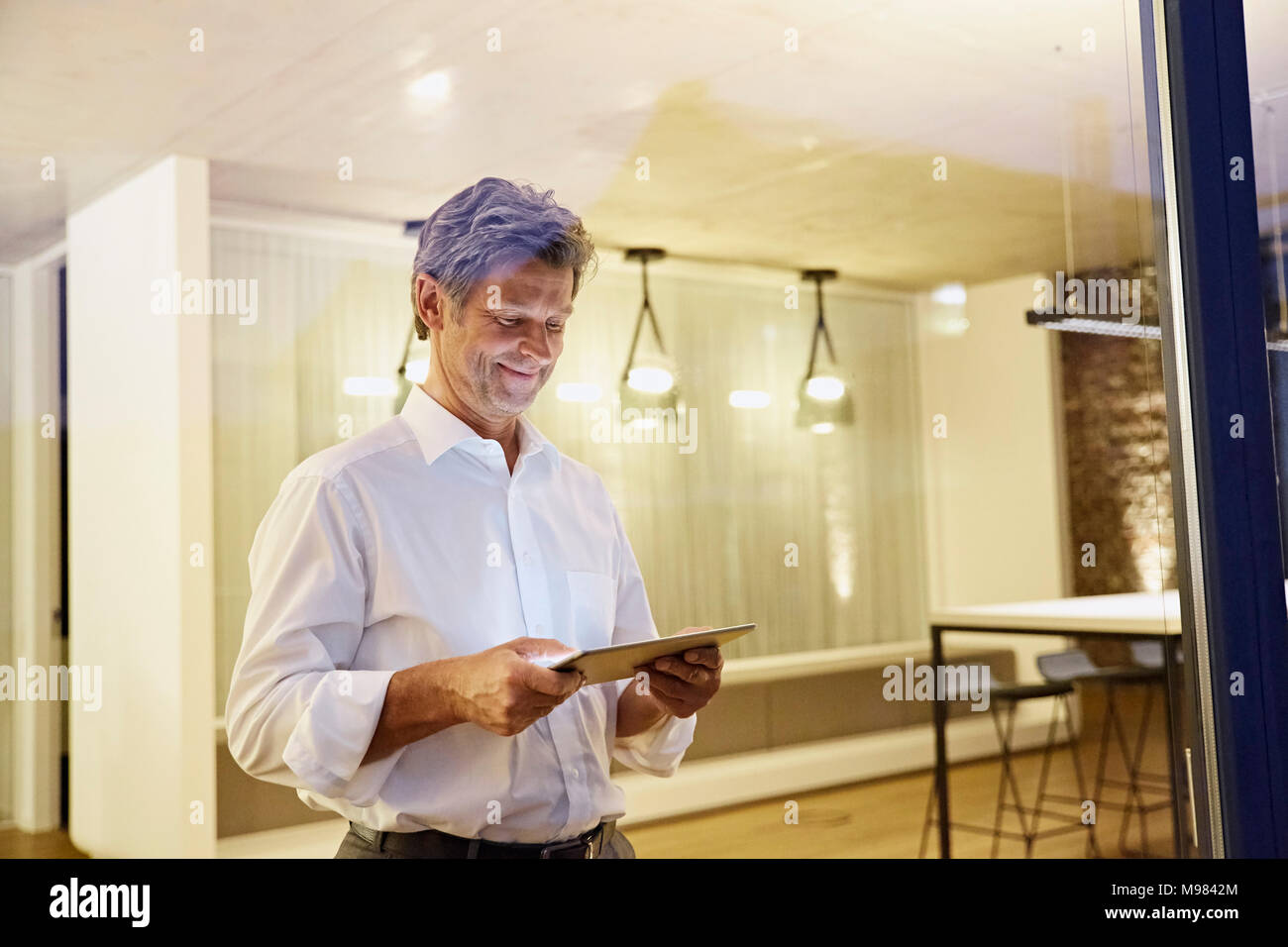 L'homme à l'aide de tablet in Modern building at night Banque D'Images