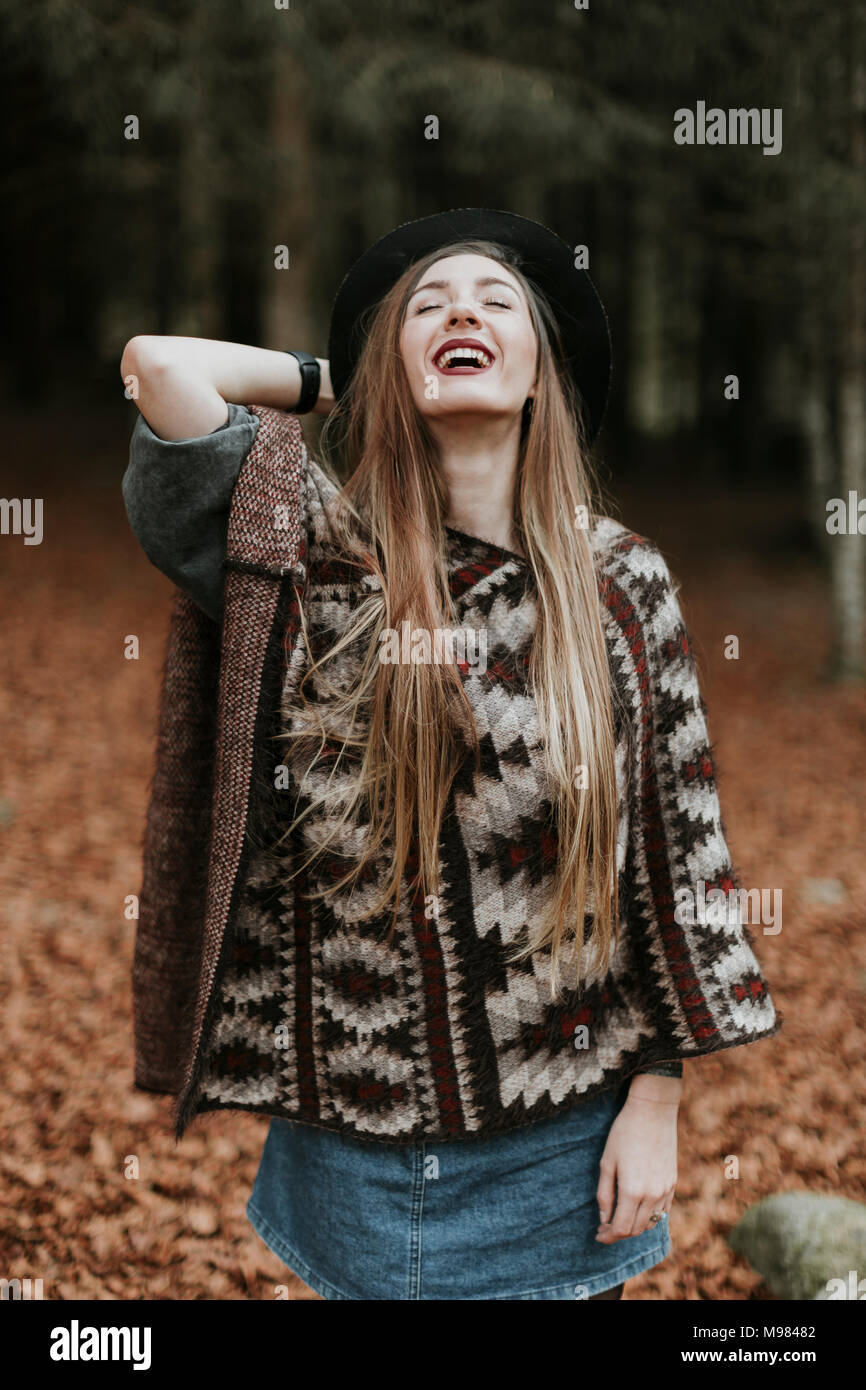 Portrait of laughing of young woman wearing hat et poncho en forêt d'automne Banque D'Images