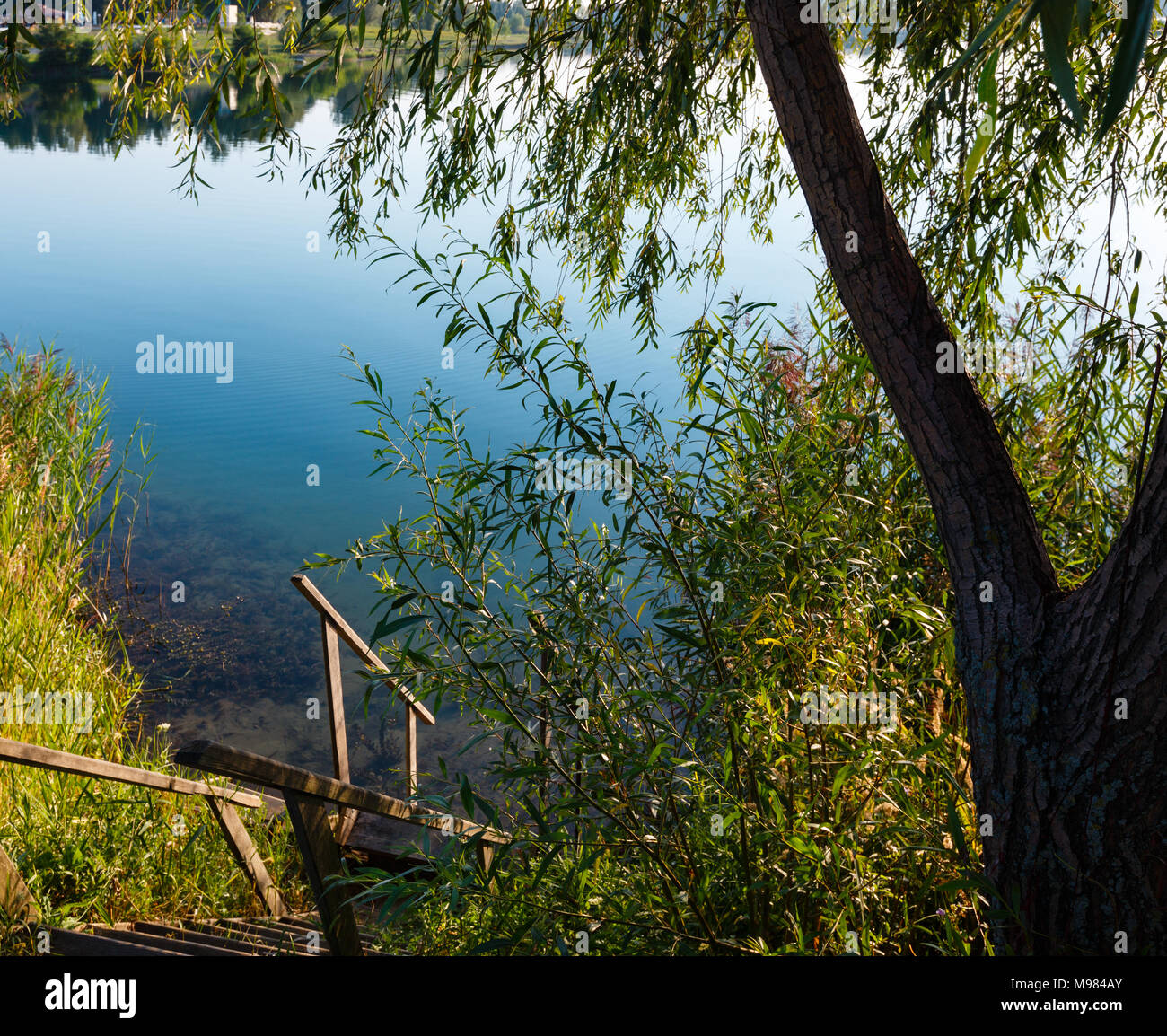 Escaliers de bois jusqu'à la pittoresque rive du lac matin d'été. Concept de la vie de campagne tranquille, éco-tourisme, le camping, la pêche. Banque D'Images