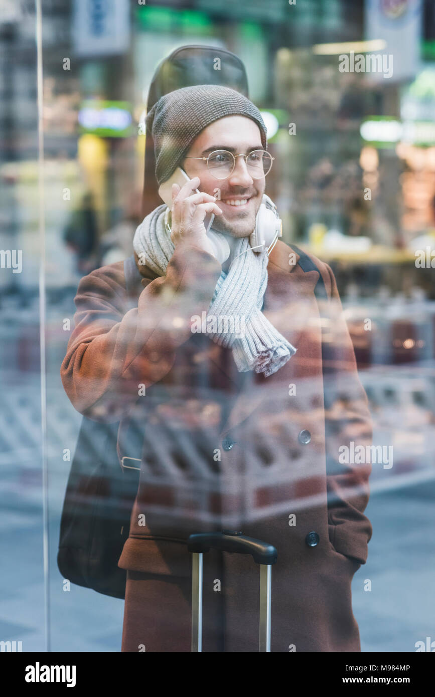 Smiling Young man with guitar case on cell phone Banque D'Images