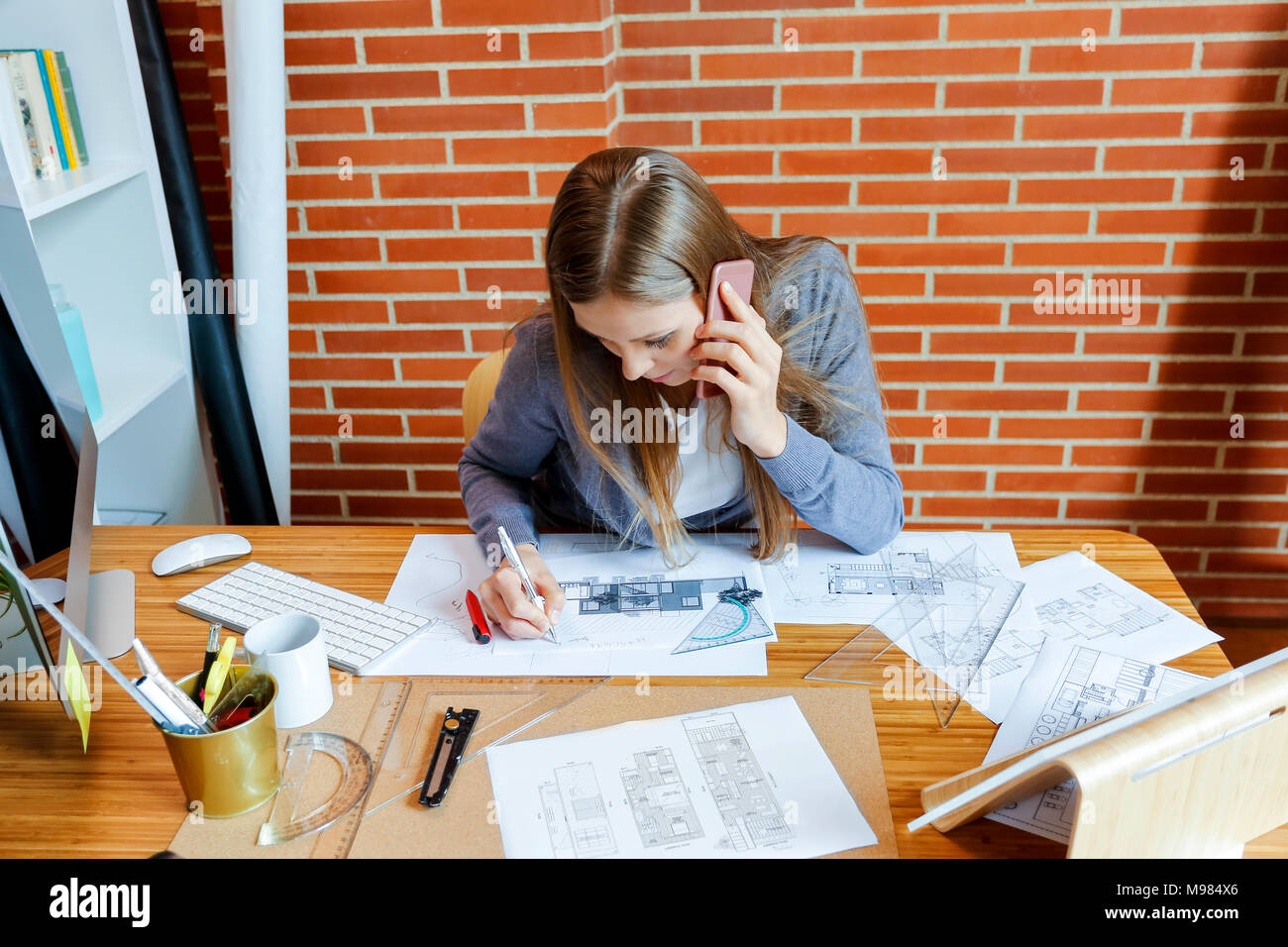 Jeune femme travaillant au bureau d'architecture, parler au téléphone Banque D'Images