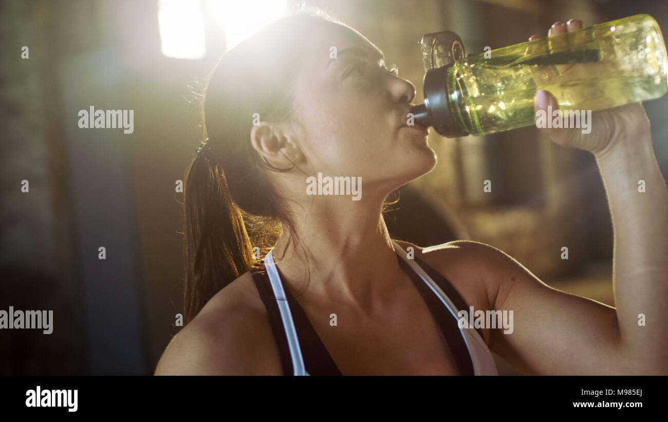 Femme athlétique solide des boissons dans une bouteille d'eau après épuisement de Cross fitness musculation Formation à son sport favori. Banque D'Images