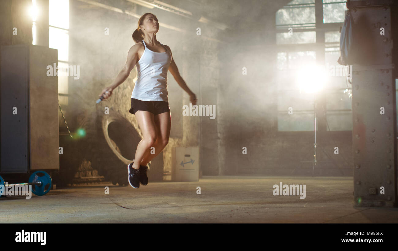 Belle femme athlétique des exercices avec Jump / la corde à sauter dans une salle de sport. Elle est couverte de sueur de sa Croix intense entraînement. Banque D'Images