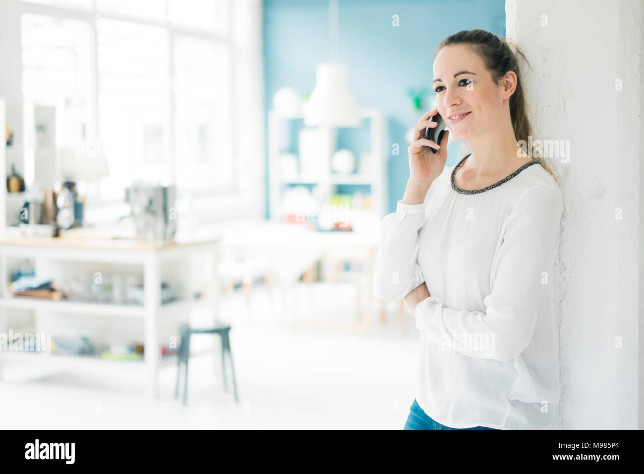 Portrait of smiling woman fils le téléphone debout dans un loft Banque D'Images Portrait of smiling woman fils le téléphone debout dans un loft Banque D'Images