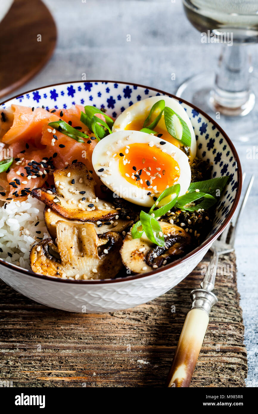 Le déjeuner bol, oeufs, riz, saumon fumé, champignons, chou vert, sésame Banque D'Images