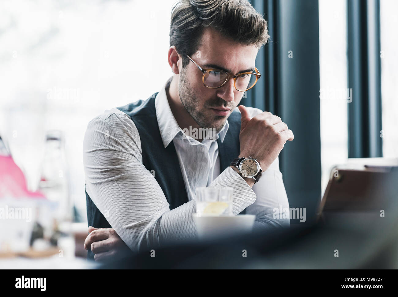 Jeune homme sérieux à l'aide de tablette dans un café Banque D'Images