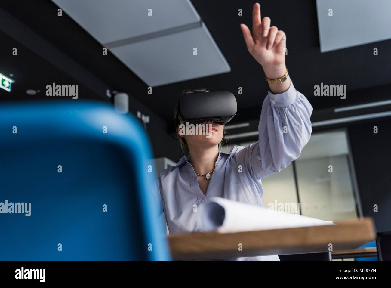 Jeune femme portant des lunettes VR à table in office Banque D'Images