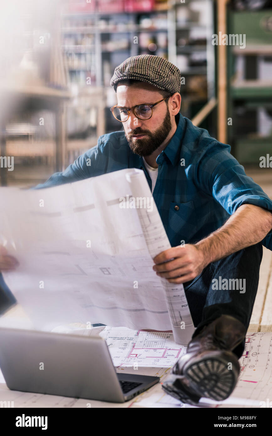 Homme assis sur le sol à la recherche au plan de construction Banque D'Images