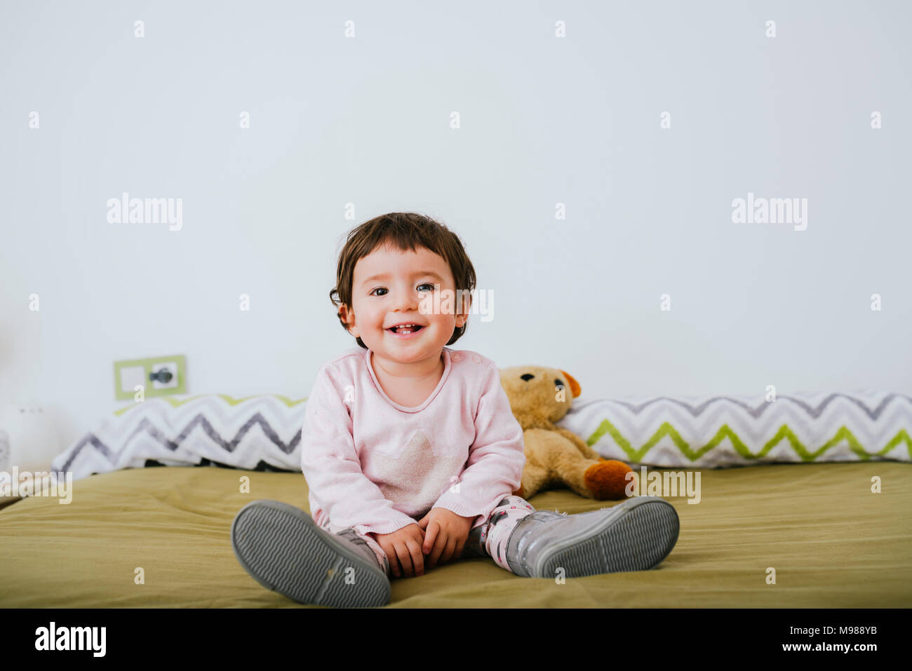 Portrait of happy baby girl sitting on bed Banque D'Images