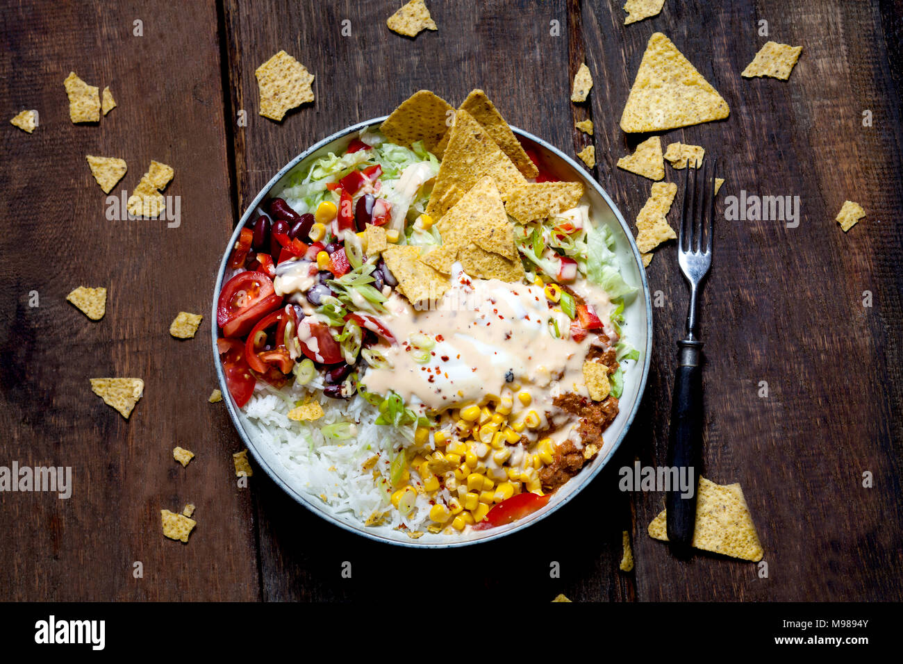 Taco salad bowl avec du riz, du maïs, du chili con carne, haricots rouges, la laitue iceberg, la crème sure, croustilles, tomates Banque D'Images