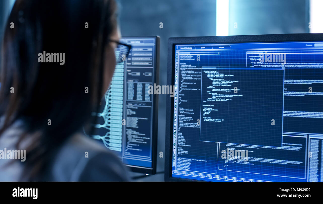 Gros plan d'une femme ingénieur travaillant en salle de surveillance. Elle travaille avec plusieurs écrans. Banque D'Images