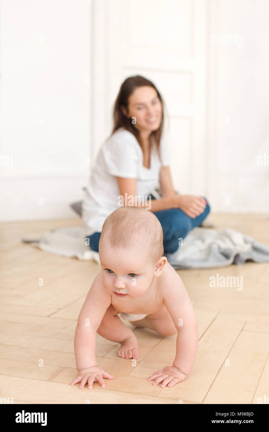 Woman watching baby crawling on floor Banque D'Images