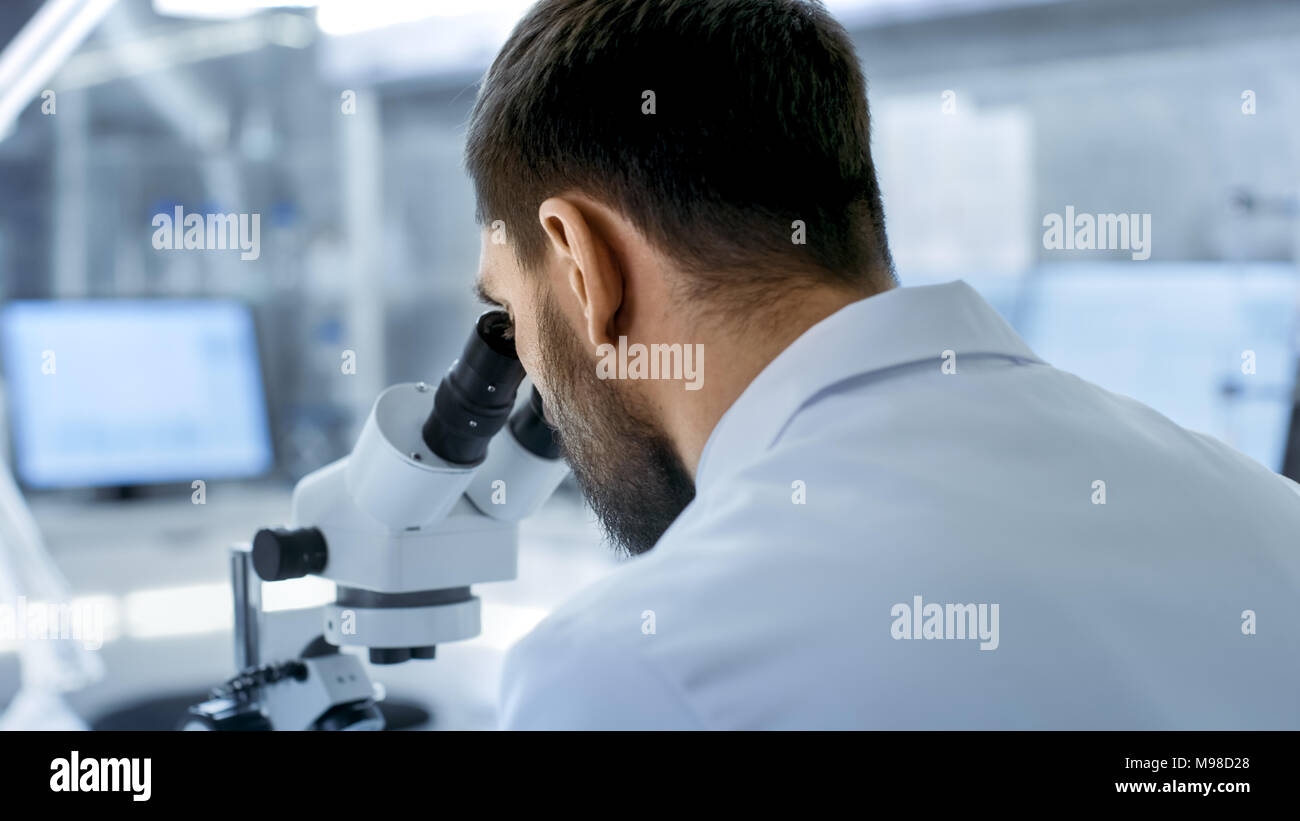 Au cours de l'épaule d'un chercheur scientifique à la recherche en microscope. Il mène des expériences avec ses collègues de laboratoire moderne. Banque D'Images