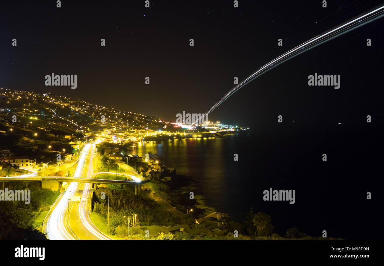 Light trails de voitures et d'un avion près de l'aéroport de Funchal, Madère Banque D'Images