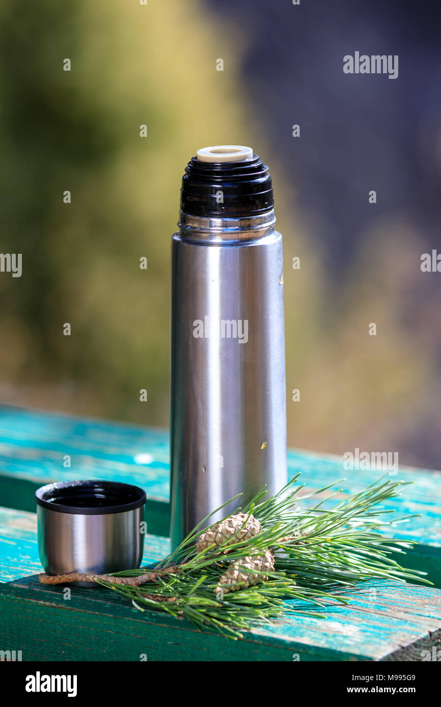 Thermos avec du thé sur un banc avec des pommes de pin Banque D'Images