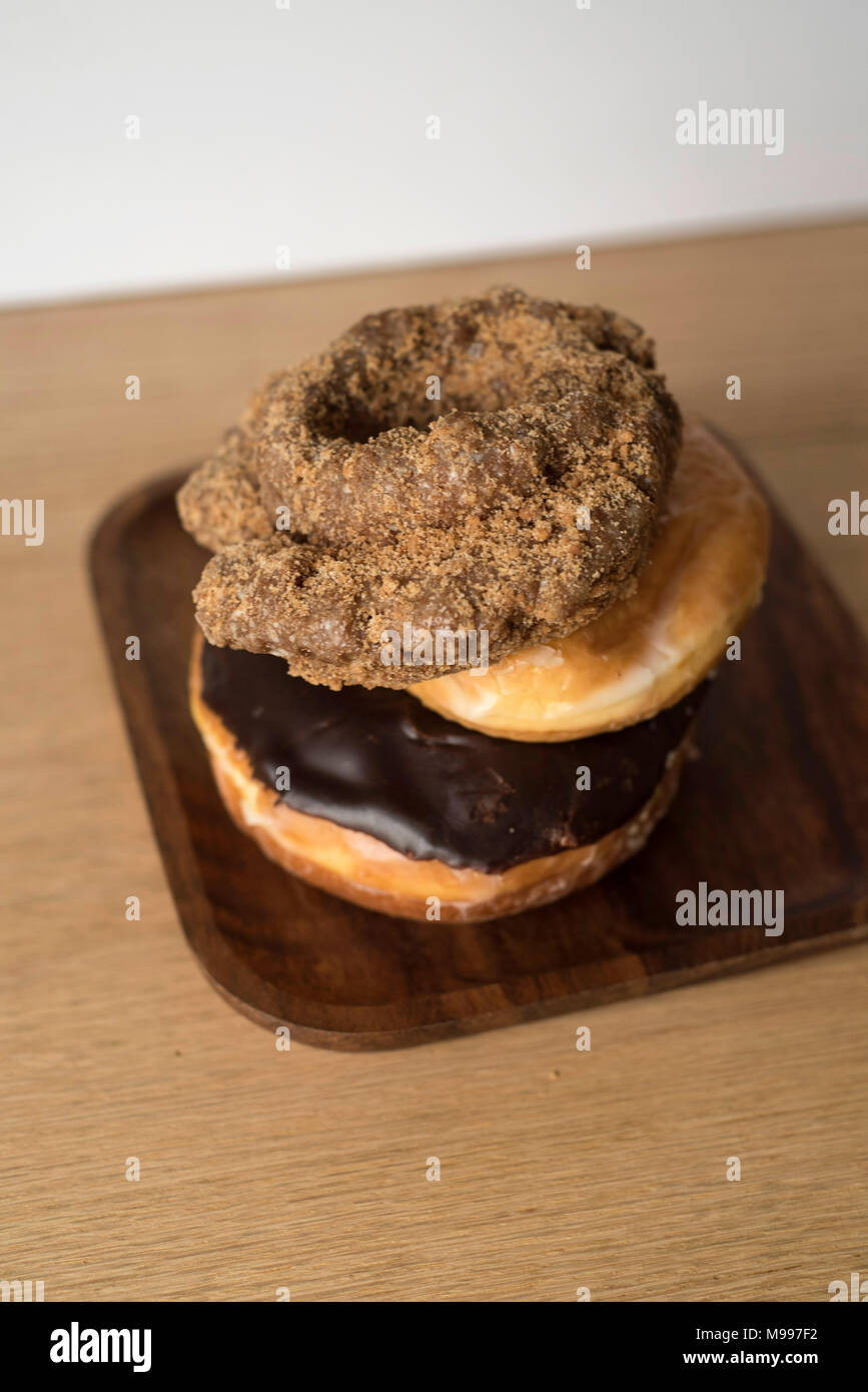 Tour penchée de donuts variété sur un comptoir en bois clair Banque D'Images