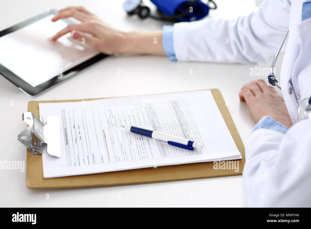 Femme médecin à l'aide de l'ordinateur tablette en position assise au bureau en gros plan de l'hôpital. Cardiologue vérifie coeur diagrammes avec tablette PC. Les soins de santé, l'assurance et de la technologie à puce dans medicine concept Banque D'Images