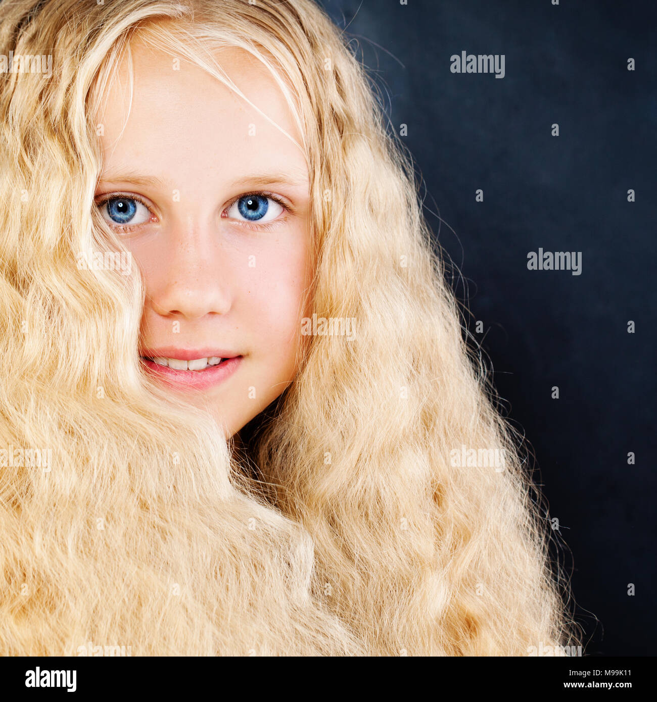 Jolie fille enfant sur fond bleu. De longs cheveux blonds, Face closeup Banque D'Images