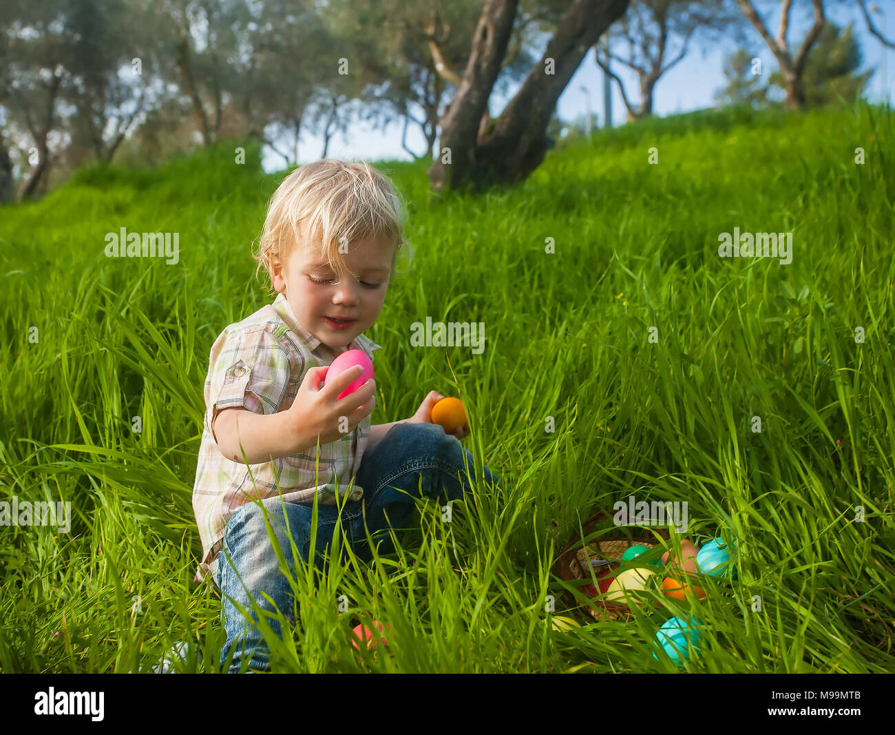 Cute toddler étudier il a trouvé les oeufs de Pâques colorés Banque D'Images