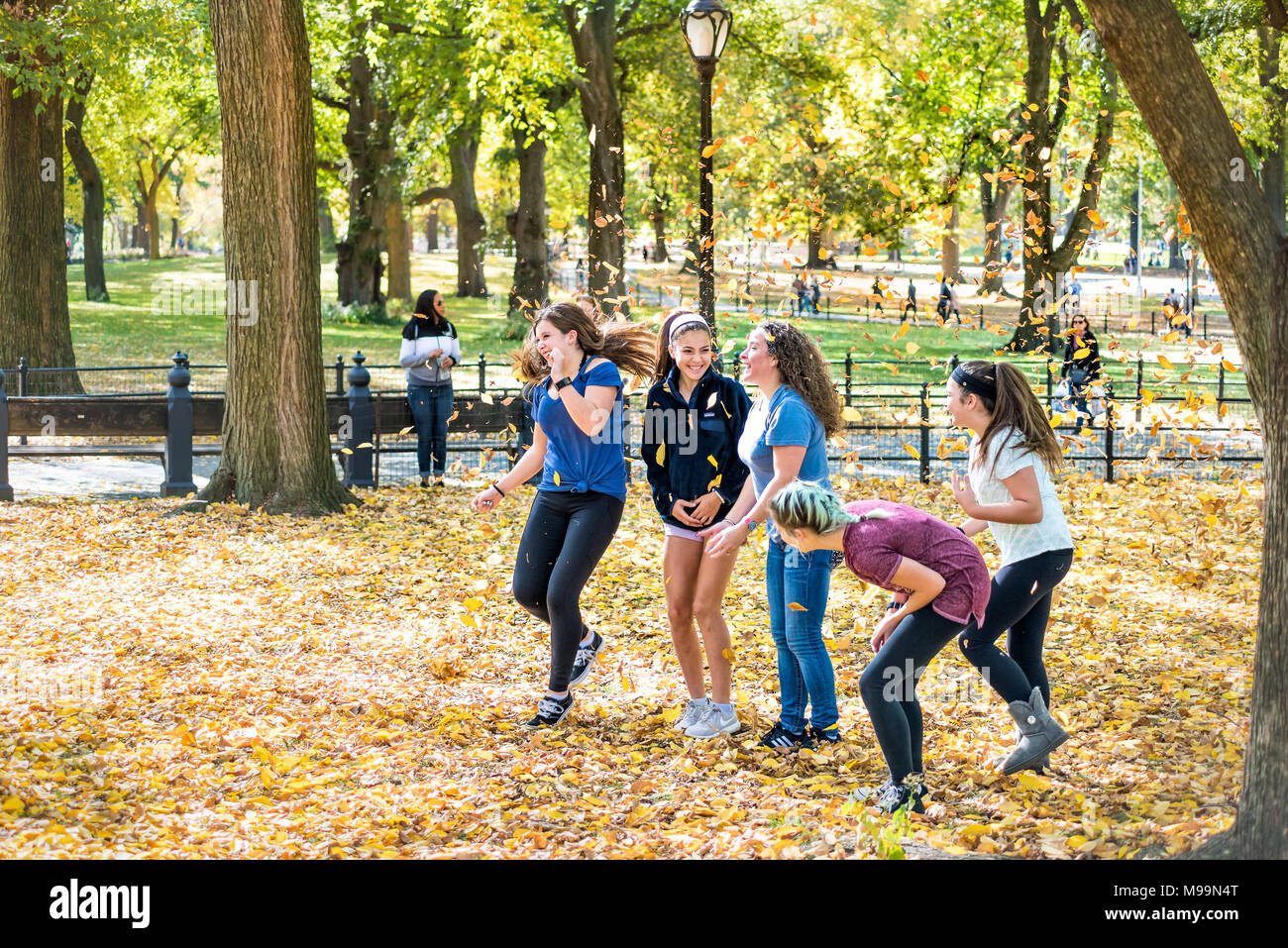 La ville de New York, USA - 28 octobre 2017 : Manhattan NYC Central Park avec des arbres, les jeunes adolescentes amis groupe de jeter les feuilles en l'air en automne Banque D'Images