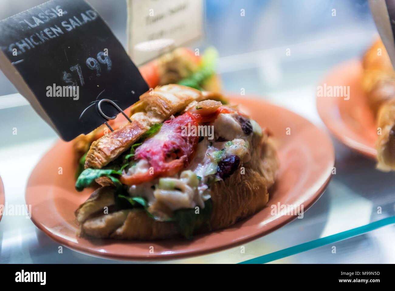 Salade de poulet sandwich classique croissant signe avec des prix sur l'écran avec du pain, fromage, viande en magasin, boutique, restauration rapide sur la plaque Banque D'Images