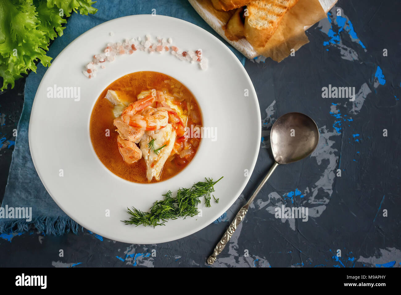 Soupe de poisson française Bouillabaisse aux fruits de mer, filet de saumon, crevettes, saveur riche, délicieux dîner dans un beau plat blanc. Close up. Spase copie Banque D'Images