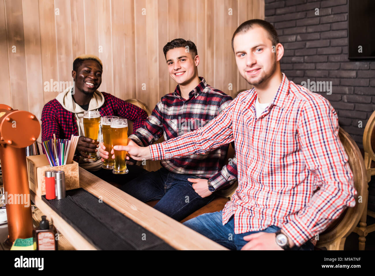 Cheerful vieux amis s'amuser et de boire la bière au comptoir du bar dans un pub. Banque D'Images