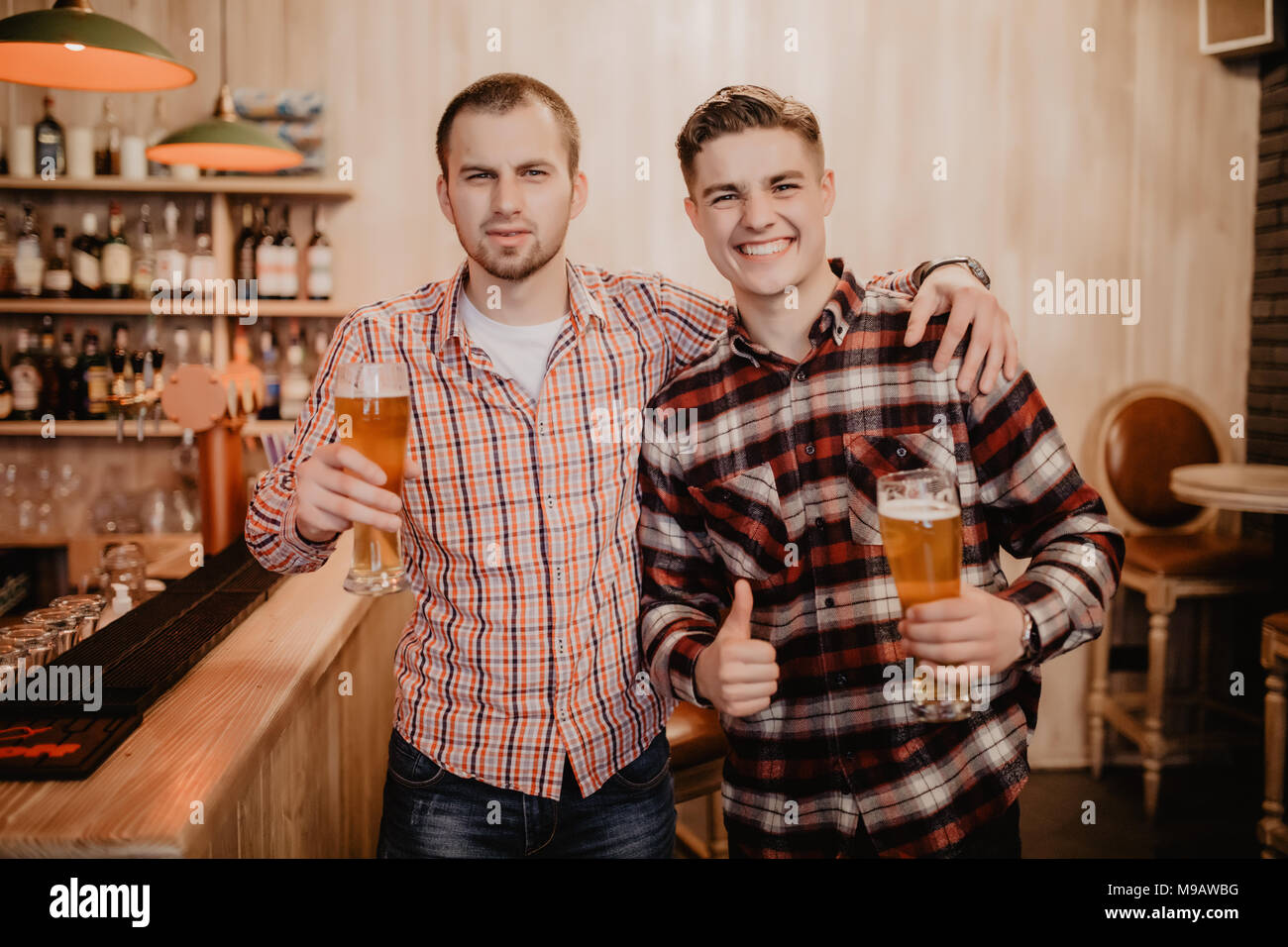 Les amis s'est réuni après une dure journée. Trois joyeux ami clink bière au bar et de boire une bière sur le bar. Banque D'Images