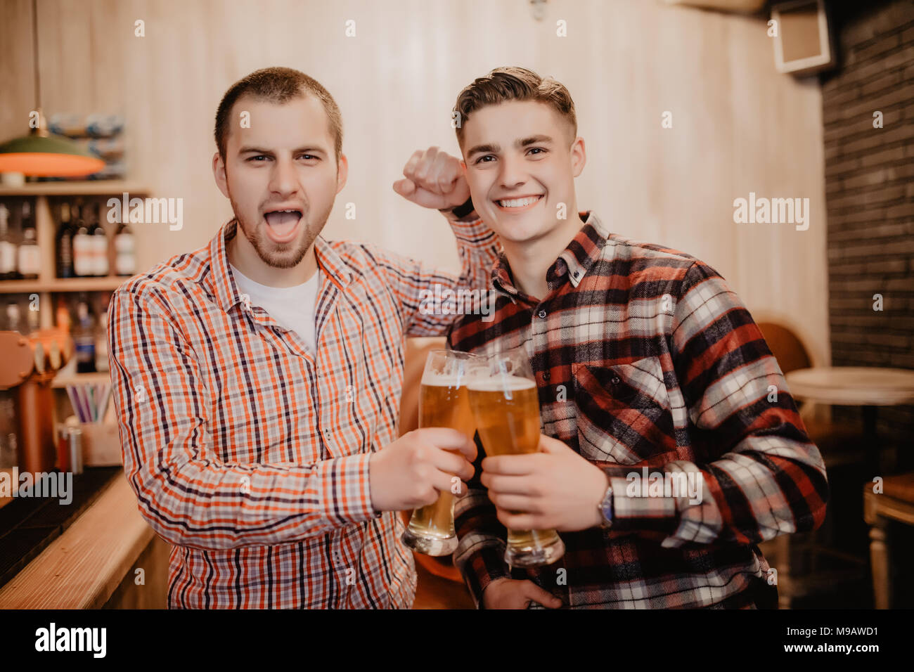 Les amis s'est réuni après une dure journée. Trois joyeux ami clink bière au bar et de boire une bière sur le bar. Banque D'Images