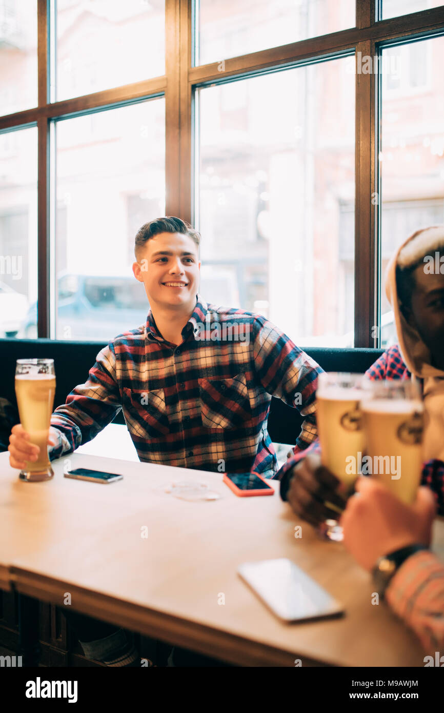 Groupe d'hommes en train de boire une bière et avoir parler dans un pub Banque D'Images