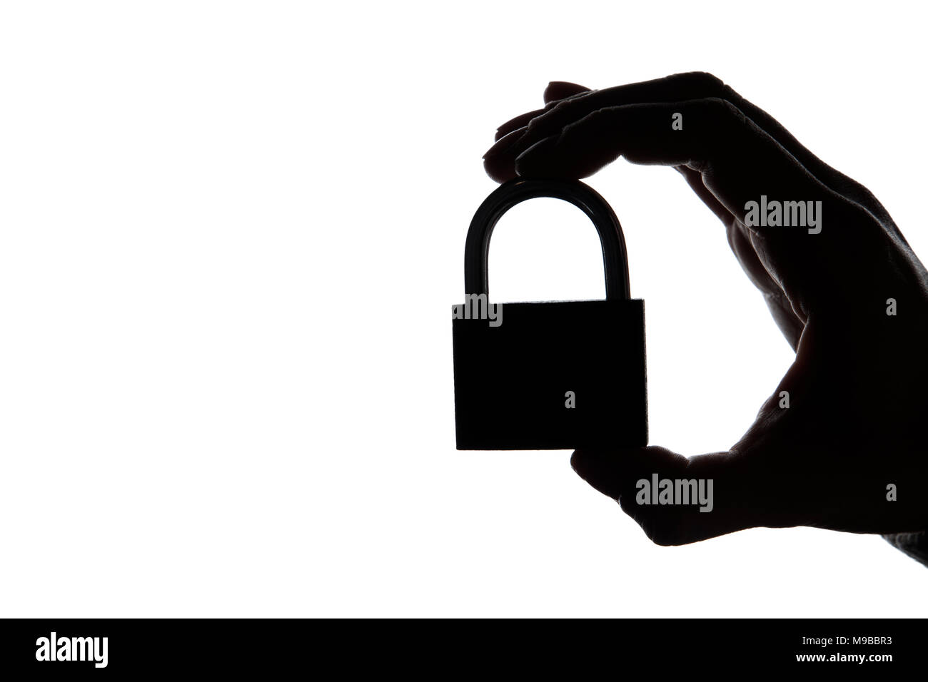 Silhouette d'une main tenant un cadenas sur un arrière-plan uni, blanc. Sécurité et confidentialité. Banque D'Images