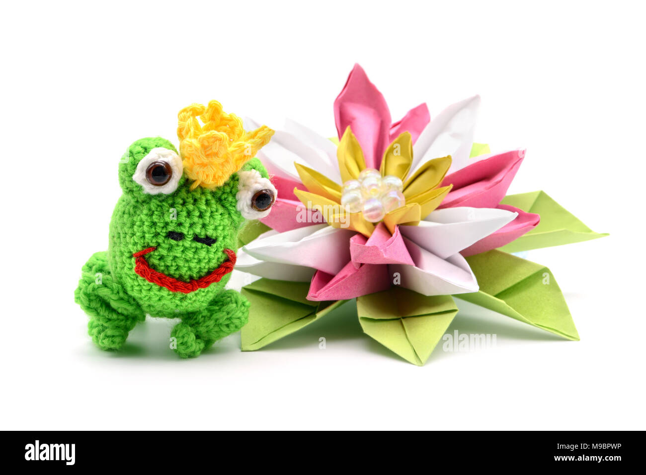 Le roi grenouille au crochet avec conte de couronne et de l'origami nénuphar sur fond blanc. Tinker. Banque D'Images